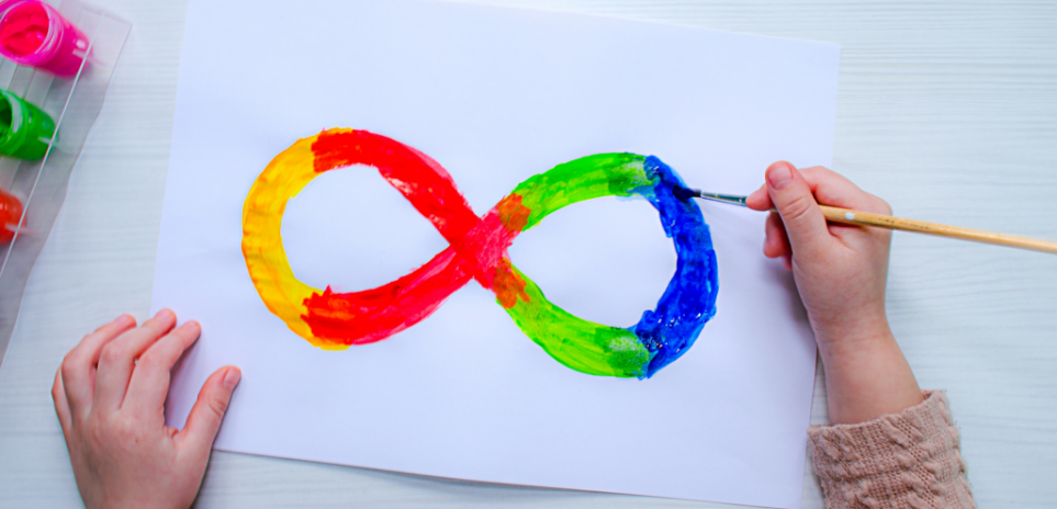 Child painting a rainbow infinity sign on a piece of paper