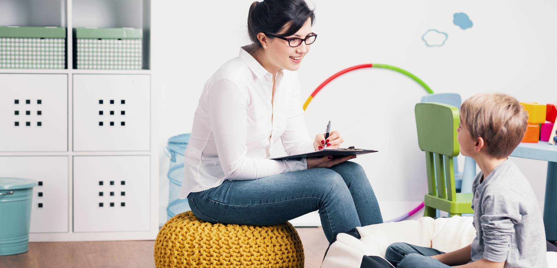 A therapist takes notes while working with a child in center