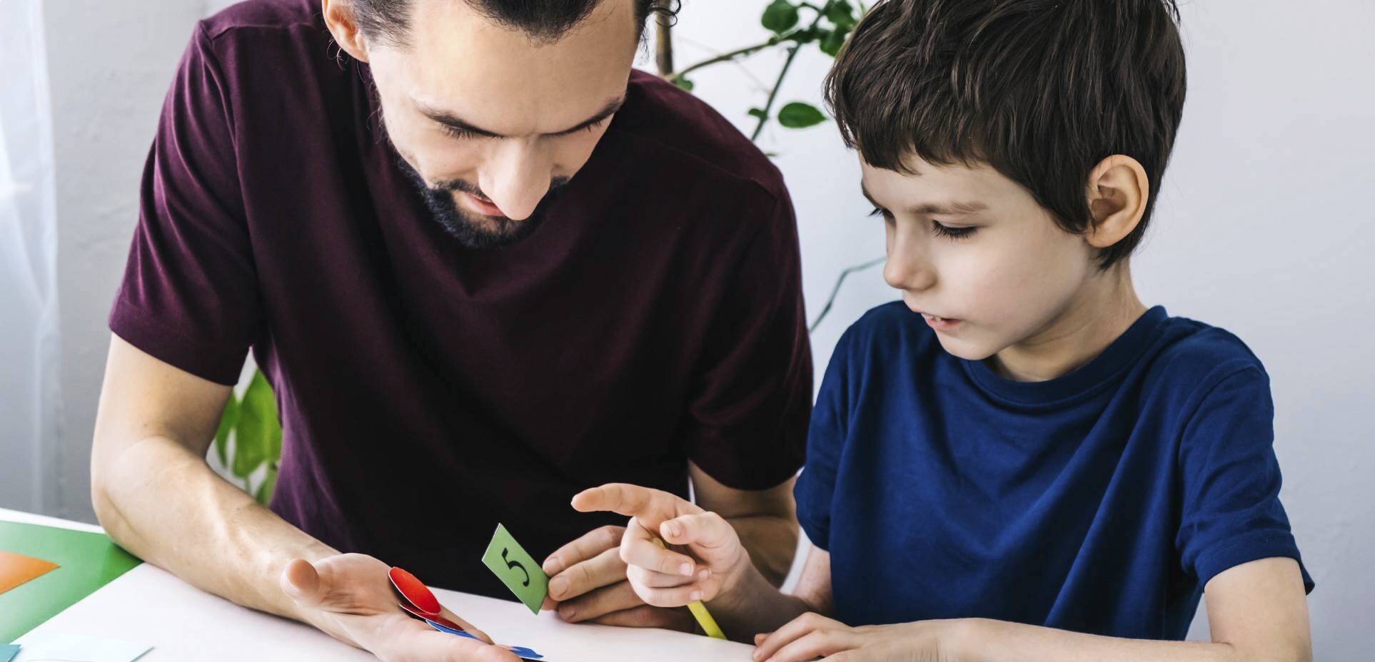 An adult assists a child with writing